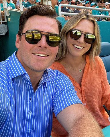 man wearing blue and white stripe polo at sports game with wife