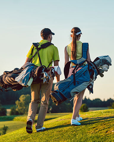 man and wife walking on golf course during tournament wearing collars and co polos