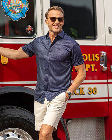 man leaning on fire truck wearing button down dress shirt