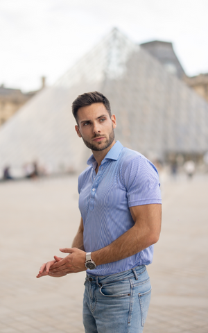 man in polo standing in front of the Louvre