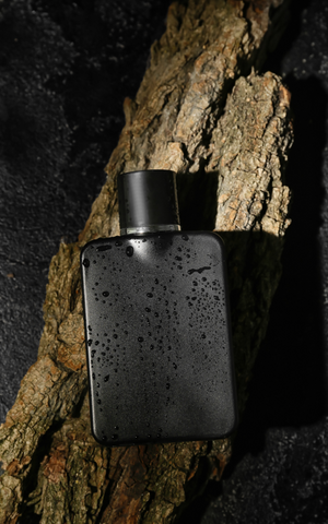 black bottle of cologne laying on a wooded surface