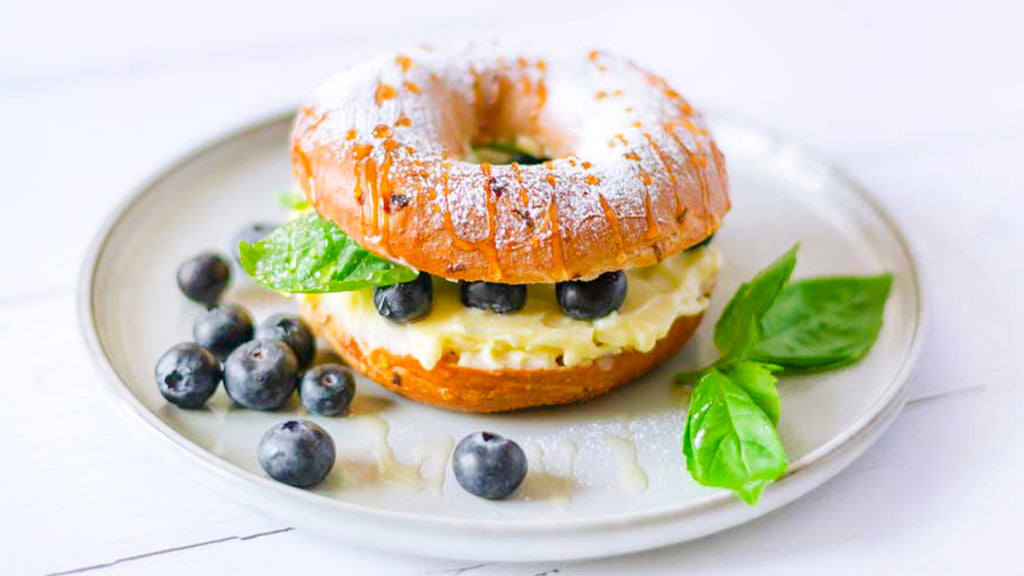 Ingredients:  For The Bagel Dough:  1 ½ cups warm water 2 ¼ tsps (1 packet) active dry yeast 4 cups bread flour 2 tbsps granulated sugar 1 ½ tsps sea salt 1 cup fresh blueberries 1 tbsp olive oil, for greasing  For The Boiling Solution:  8 cups water ¼ cup honey or barley malt syrup 1 tablespoon baking soda  For The Topping:  1 egg, beaten (for egg wash) Sesame seeds or poppy seeds (optional)  Instructions:  In the bowl of your Kitchenin KM50 Stand Mixer, combine the warm water and active dry yeast. Let it sit for about 5-10 minutes until foamy.  Attach the dough hook to your stand mixer. Add the bread flour, granulated sugar, and salt to the bowl with the activated yeast.   Mix on low speed until a dough starts to form. Increase the speed to medium and knead the dough for about 5-7 minutes until it becomes smooth and elastic.  Add the fresh blueberries to the dough and knead on low speed for another 2-3 minutes until the blueberries are evenly distributed throughout the dough.  Lightly grease a large bowl with olive oil. Transfer the dough to the greased bowl, cover with a clean kitchen towel, and let it rise in a warm, draft-free place for about 1-1.5 hours or until doubled in size.  Once the dough has risen, punch it down to release the air bubbles. Divide the dough into 8 equal portions. Roll each portion into a ball and then use your fingers to poke a hole in the center to form the bagel shape. Place the shaped bagels on a lightly floured surface, cover with a kitchen towel, and let them rest for about 10-15 minutes.  While the bagels are resting, preheat your oven to 425°F in advance. Line a baking sheet with parchment paper and set aside.  In a large pot, bring the water, honey (or barley malt syrup), and baking soda to a boil.   Once boiling, carefully drop 2-3 bagels into the boiling water at a time. Boil for about 1 minute on each side, then remove with a slotted spoon and place them on the prepared baking sheet.  Brush the tops of the boiled bagels with beaten egg wash. If desired, sprinkle sesame seeds or poppy seeds on top for added flavor and texture.  Transfer the baking sheet to the preheated oven and bake the bagels for 20-25 minutes or until golden brown and cooked through.  Once baked, remove the bagels from the oven and let them cool on a wire rack for a few minutes. Serve warm or at room temperature, and enjoy!