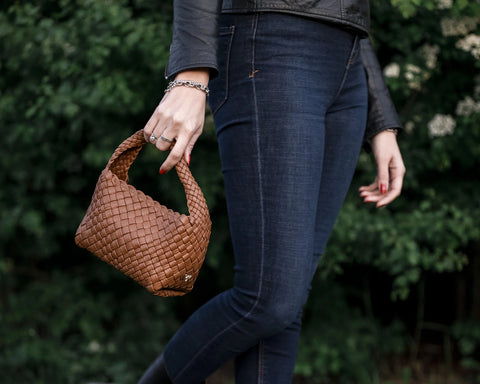 a woman outdoor with a small woven Ghibli brown bag in a hand