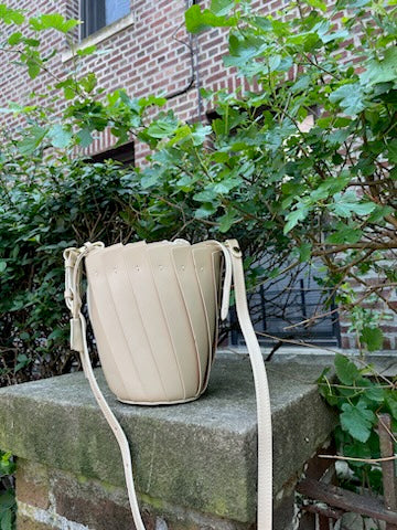 ivory boldrini selleria handbag on the stone with street greens on background