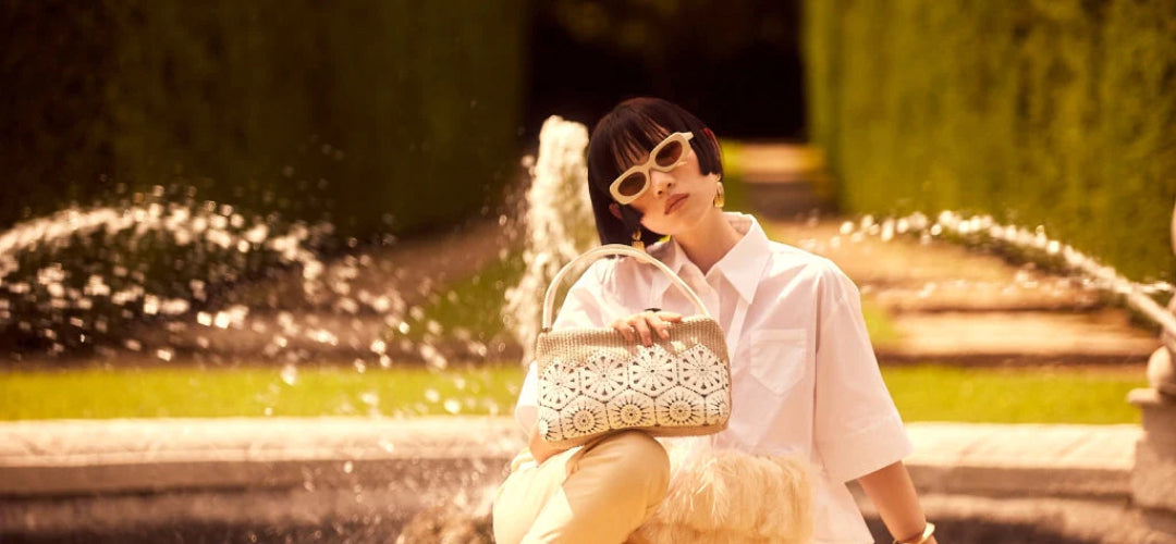 A young woman enjoying the sunshine in the park, clutching a designer handbag.