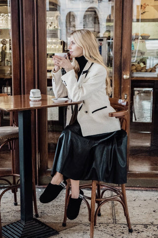 a stylish well dressed young woman sitting at the coffee bar table