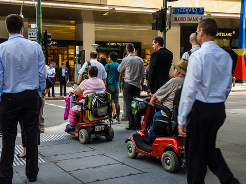 people crossing street including 2 mobility scooters