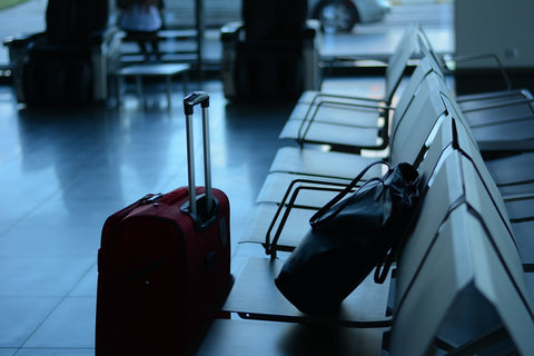 chairs at an airport with bag on seat and luggage on ground