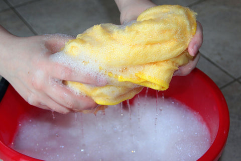 red cleaning bucket with hand wringing out soapy cloth