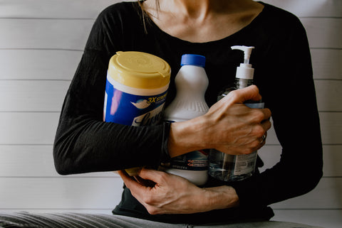 women in black shirt holding three cleaning products