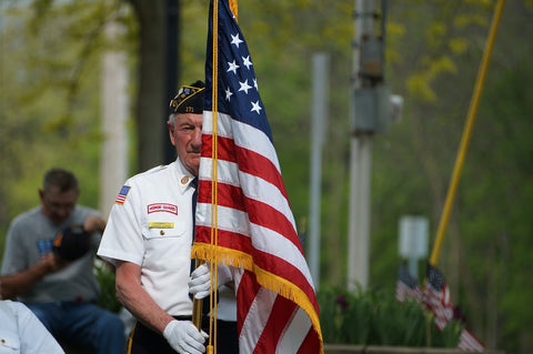 Older veteran holding American flag outside