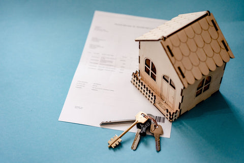 mini wooden house and keys on top of paper