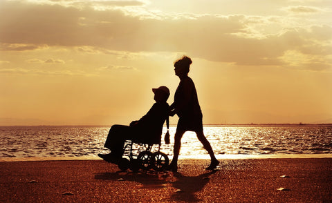 person in wheelchair on the beach at sunset