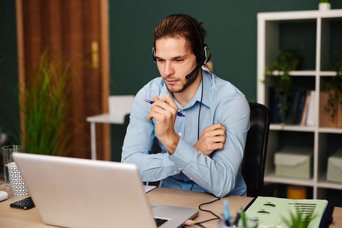 man with headset in front of a laptop