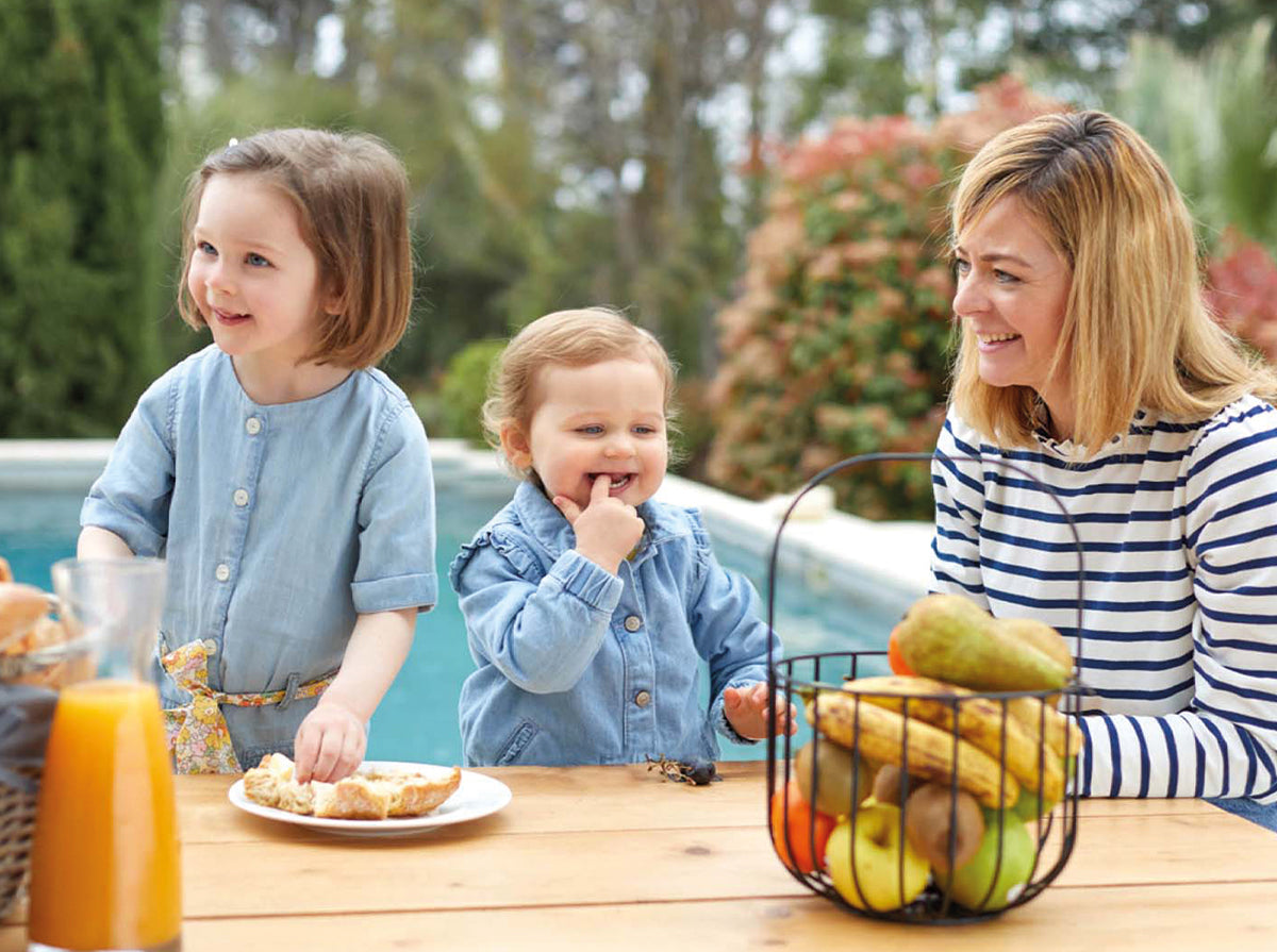 Un panier gourmand servi sur le pas de la porte rempli de bons produits pour un petit déjeuner au lit, dans la salle à manger ou au bord de la piscine