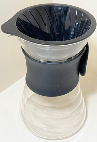 Hair v60 Carafe. Hourglass shaped carafe with silicone grip band around the middle. Plastic conical insert in the top that fits the filter paper. Pour over coffee dripper.