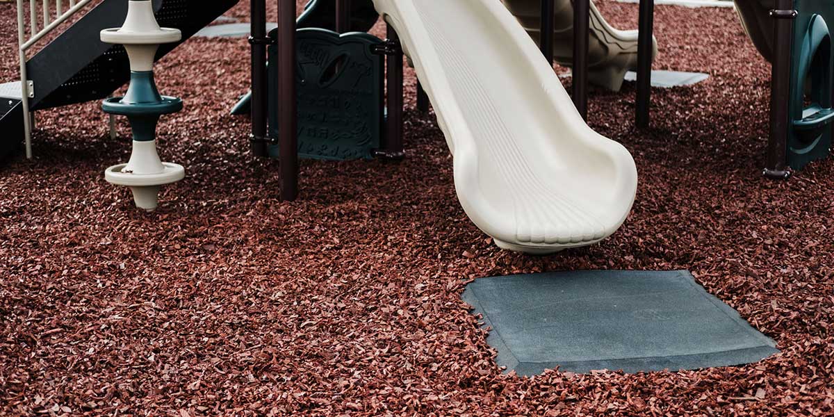 Square playground mat under a slide