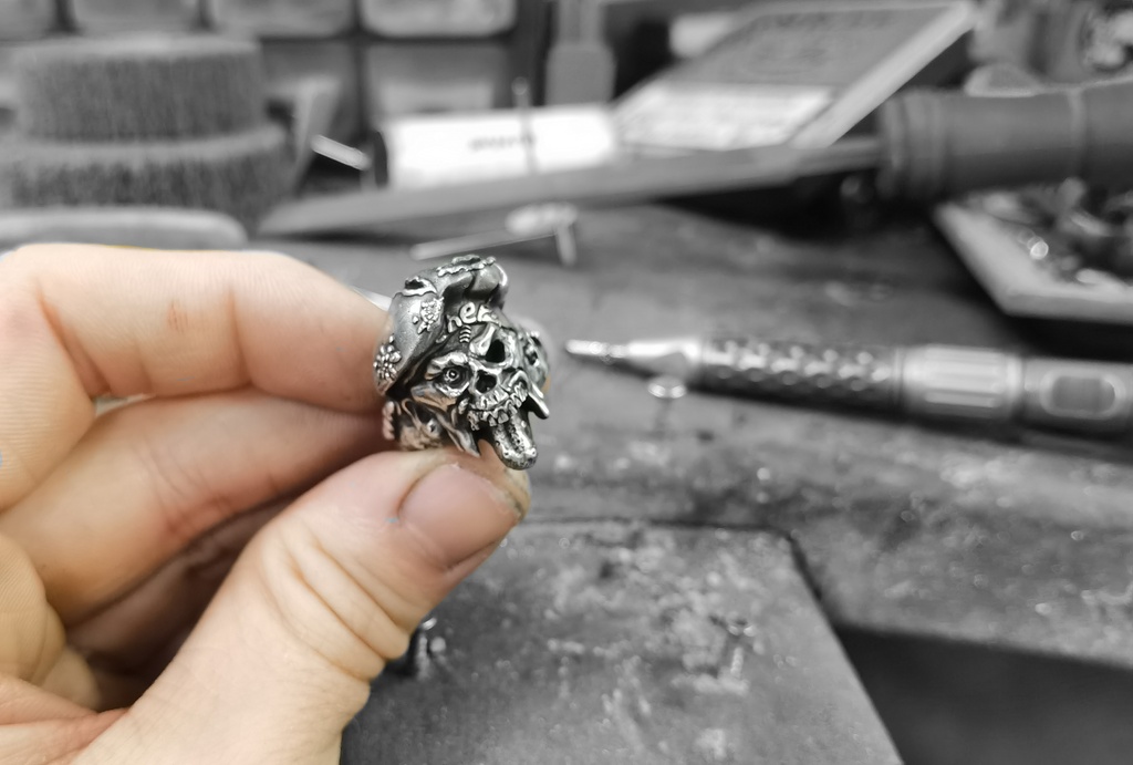 craftsman holding a silver zombie freakshow ring in his hand 