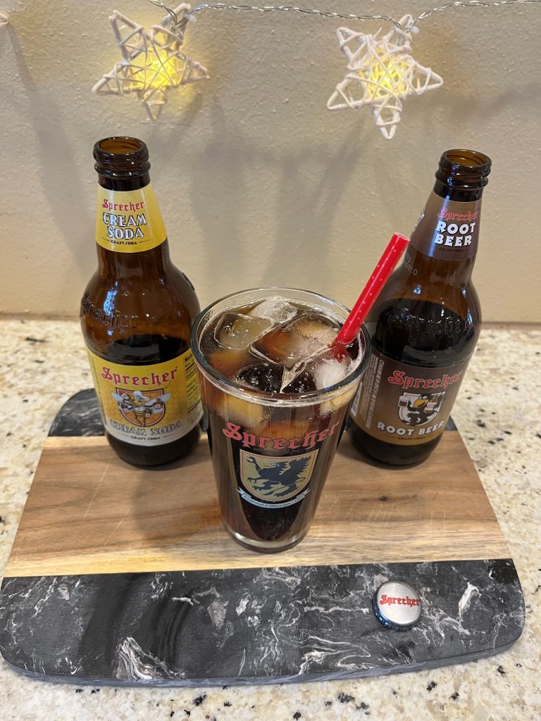 A bottle of sprecher cream soda next to a cream soda iced coffee mocktail in a pint glass