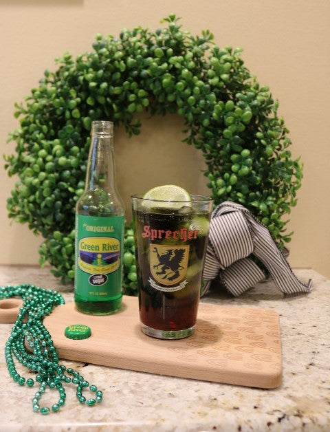 Green river soda bottle next to a pint glass with a cocktail inside