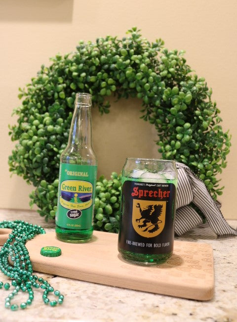 Green river soda bottle next to a pint glass with a cocktail inside