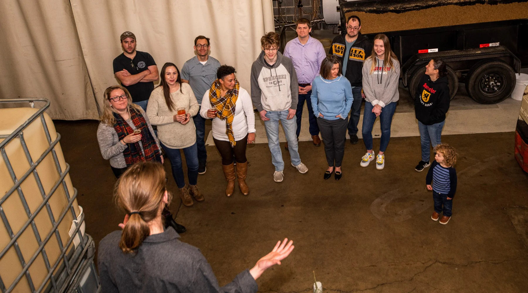 People cheersing sprecher beers and sodas in a taproom, smiling woman in the background.