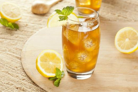 Glass of iced tea with mint and lemons on a wood tray