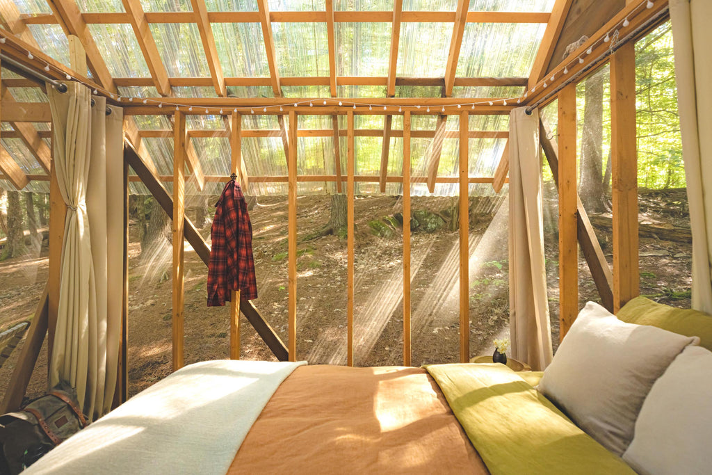 The cozy bed in Tanglebloom Cabin with window walls in the forest