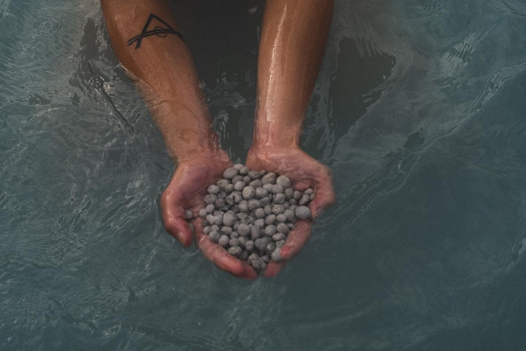 hands holding stones in water for meaningful bathing
