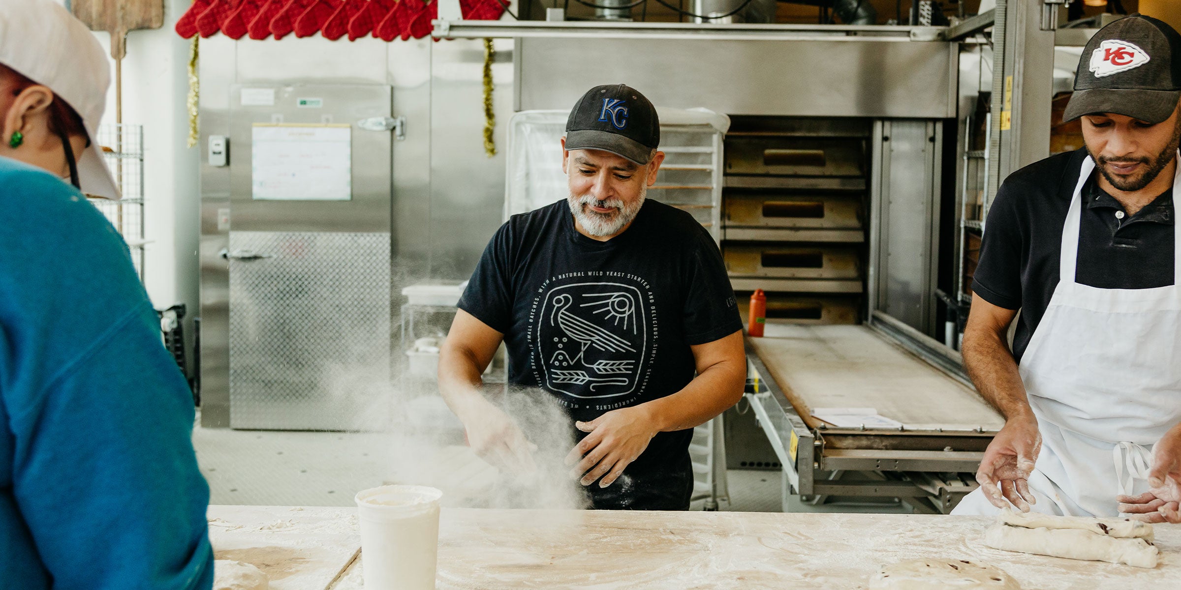 Rodrigo shaking out flour onto counter in baking area of Messenger Grand