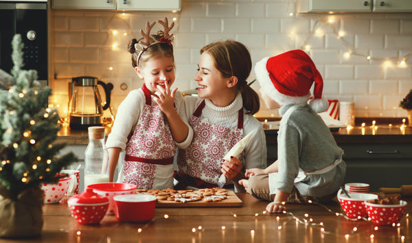 woman baking christmas cookies with two children