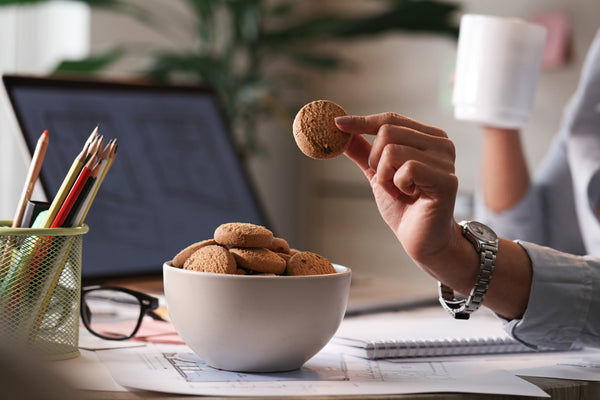woman eating cookies from a bowl while working