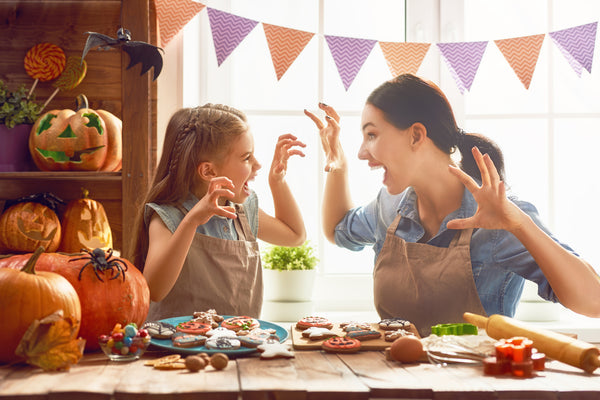 mother and daughter having fun while decorating halloween cookies