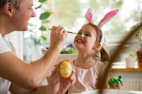 Father and daughter decorating eggs with a paintbrush