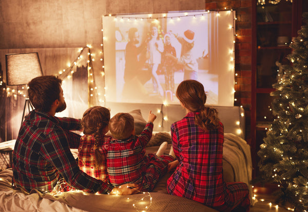 Mother and father watching Christmas movies  on a projector with their children