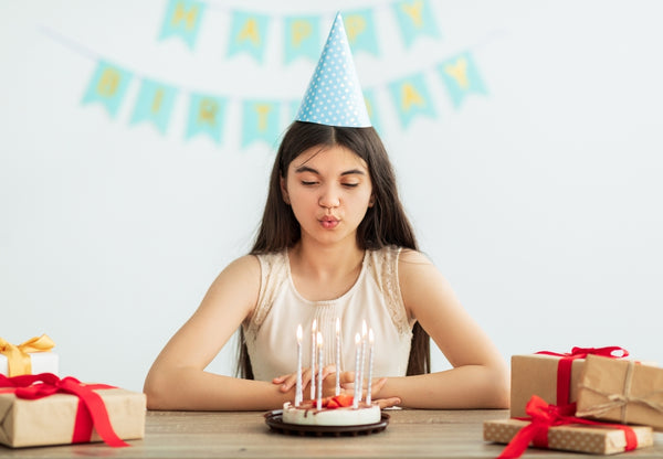 Young teen girl blowing out candles and birthday party