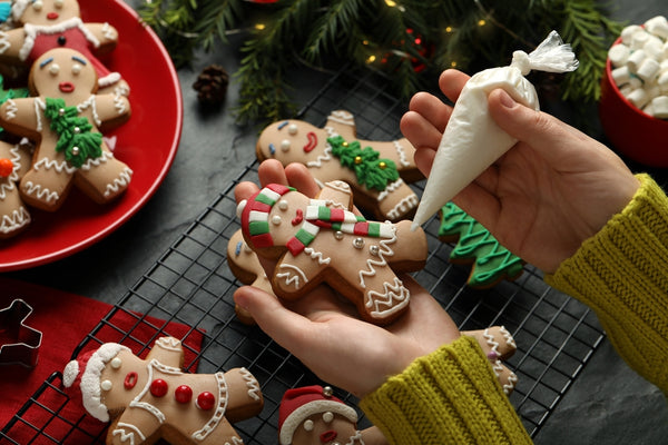 Girl decorating festive gingerbread cookies with piping bag for icing