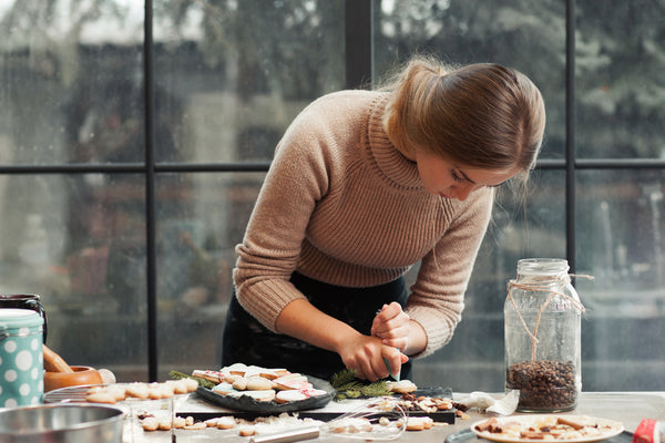 Woman carefully decorating cookies with piping bag
