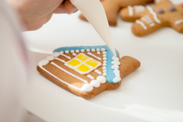 Closeup of a person carefully decorating a house-shaped cookie