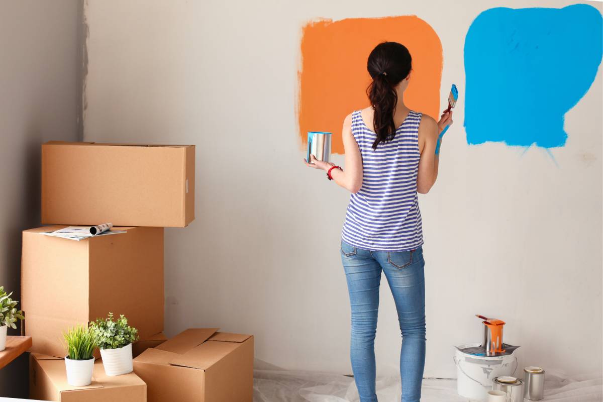 Woman deciding between an orange or blue interior paint swatch in a new house