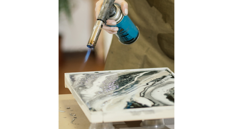 Using a flame torch to pop bubbles on the surface of the resin