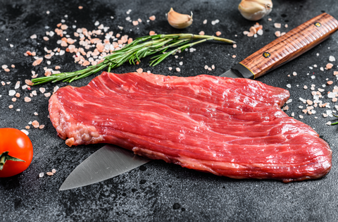Raw Flank Steak on a slate board with a knife