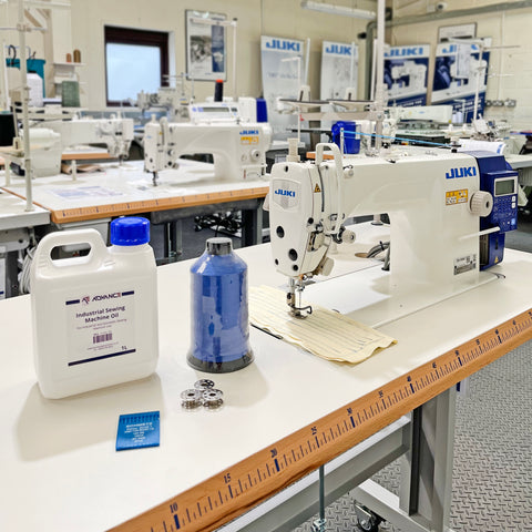 Oil, thread, bobbins, and needles on a sewing machine table