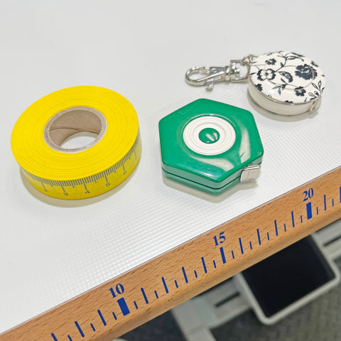 Image of 3 different tape measures on a sewing machine table