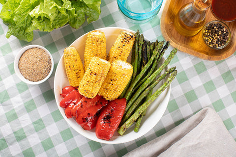 A bowl of chargrilled veggies, including cobs of corn, asparagus and red capsicum