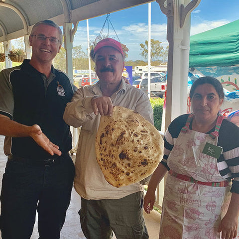 Jeff with Dakhil and Nofa sharing their traditional Yazidi flatbread, baked onsite for the event.