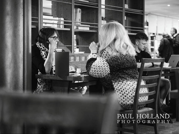 Black and white image shows two women seated in a cafe
