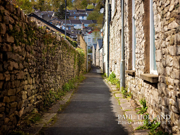 Colour photos showing a walkway with a stone wall on the left and a row of old cottages on the right