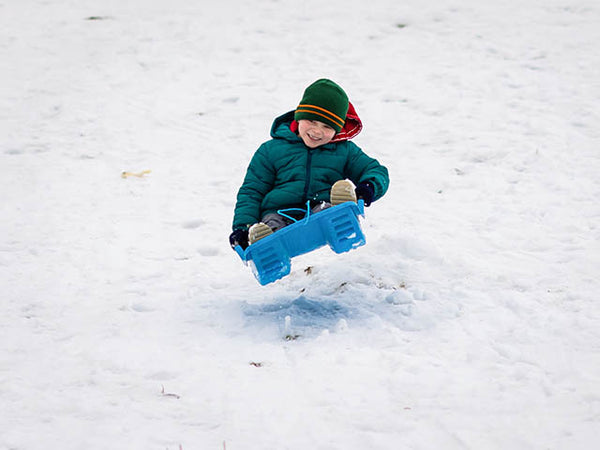 Young boy in a sledge takes off from the ground