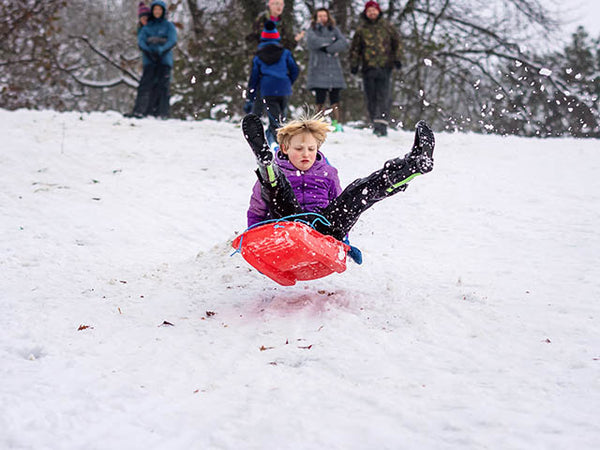 Image shows a child on a red sledge in mid air